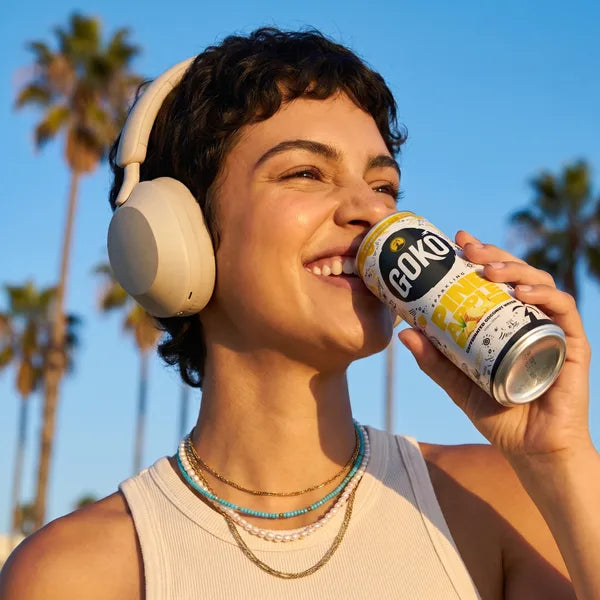 Woman with headphones drinking a GOKO Pineapple can